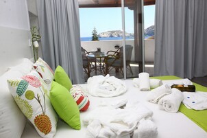 Una habitación de hotel con cama, almohadas, toallas, una botella y una mesa con sillas.