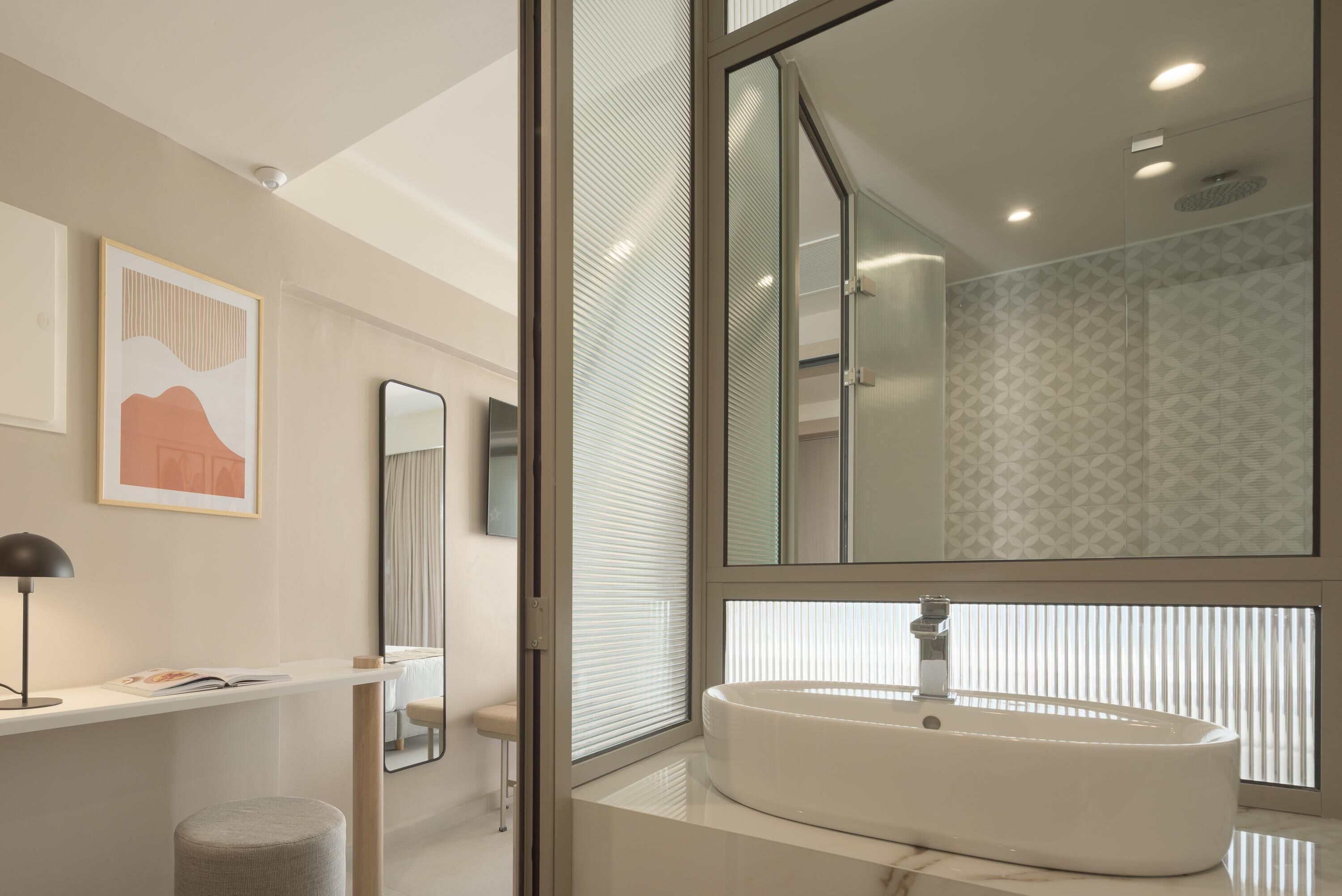 A modern bathroom with a large mirror, a white sink, and a window with blinds.
