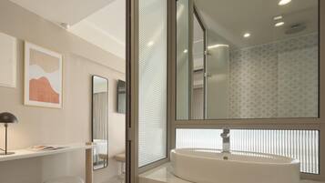 A modern bathroom with a large mirror, a white sink, and a window with blinds.