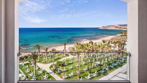 A balcony with a view of a beach and a resort area with rows of sun loungers and umbrellas. - Creta Star Hotel (Rethymno)