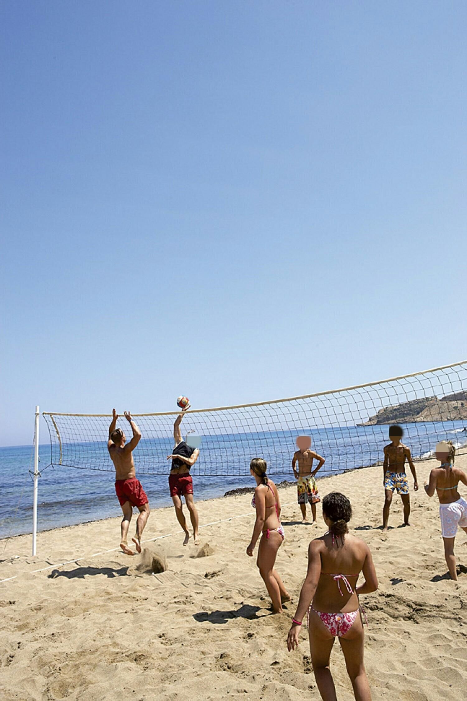 A beach volleyball game with players in swimwear.