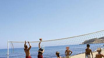 A beach volleyball game with players in swimwear.