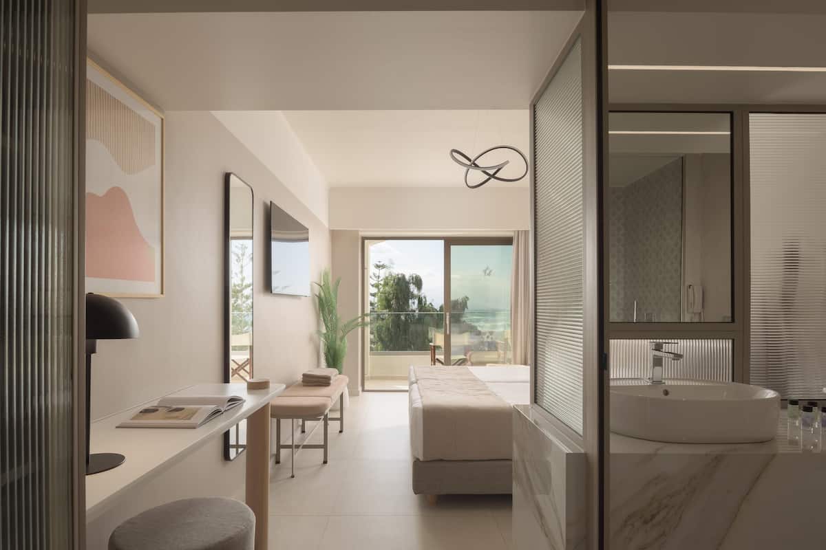 A modern bathroom with a large bathtub, a mirror, and a view of the outdoors.