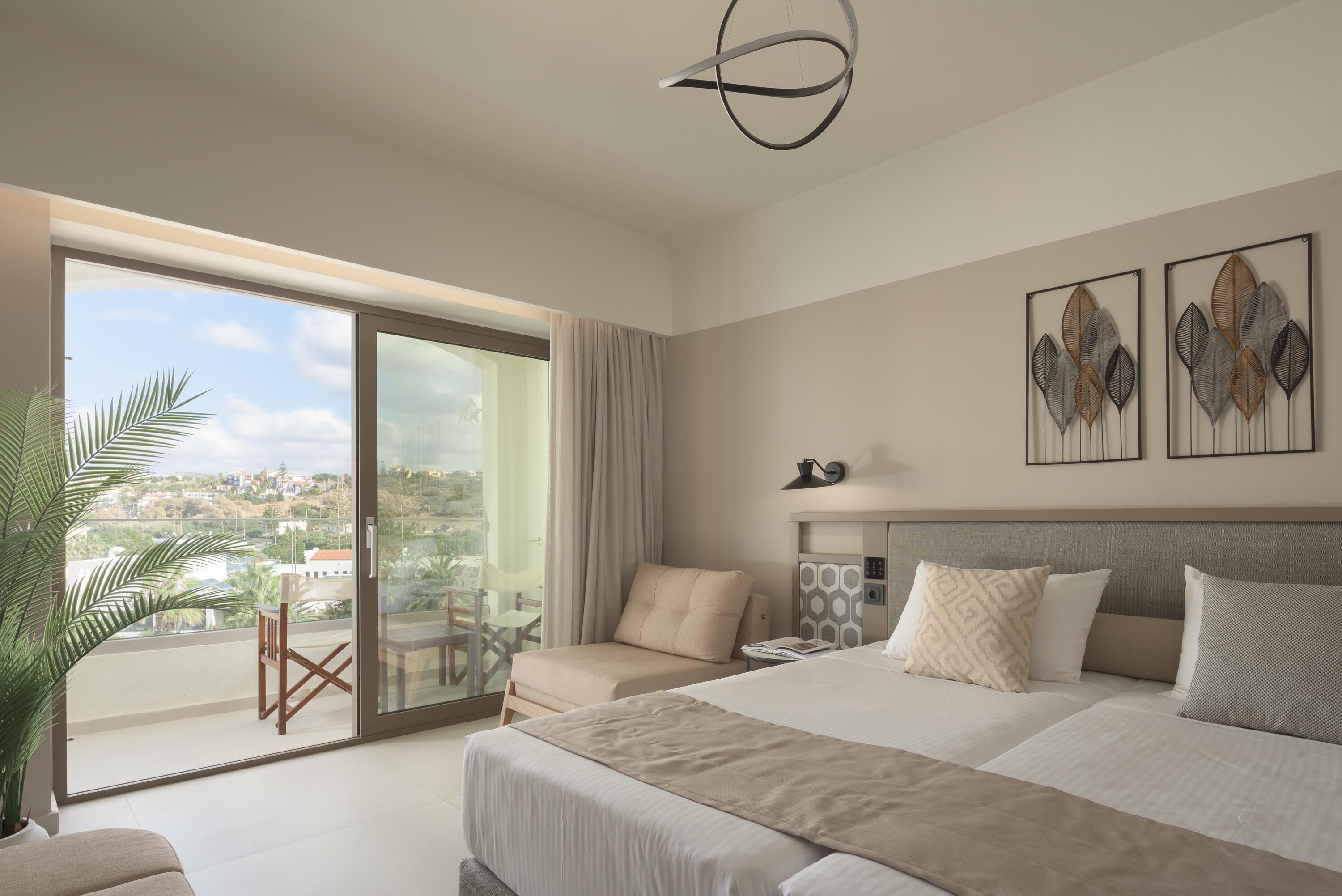 Habitación de hotel moderna con una cama grande, un balcón con vistas a la ciudad, un escritorio y una silla.
