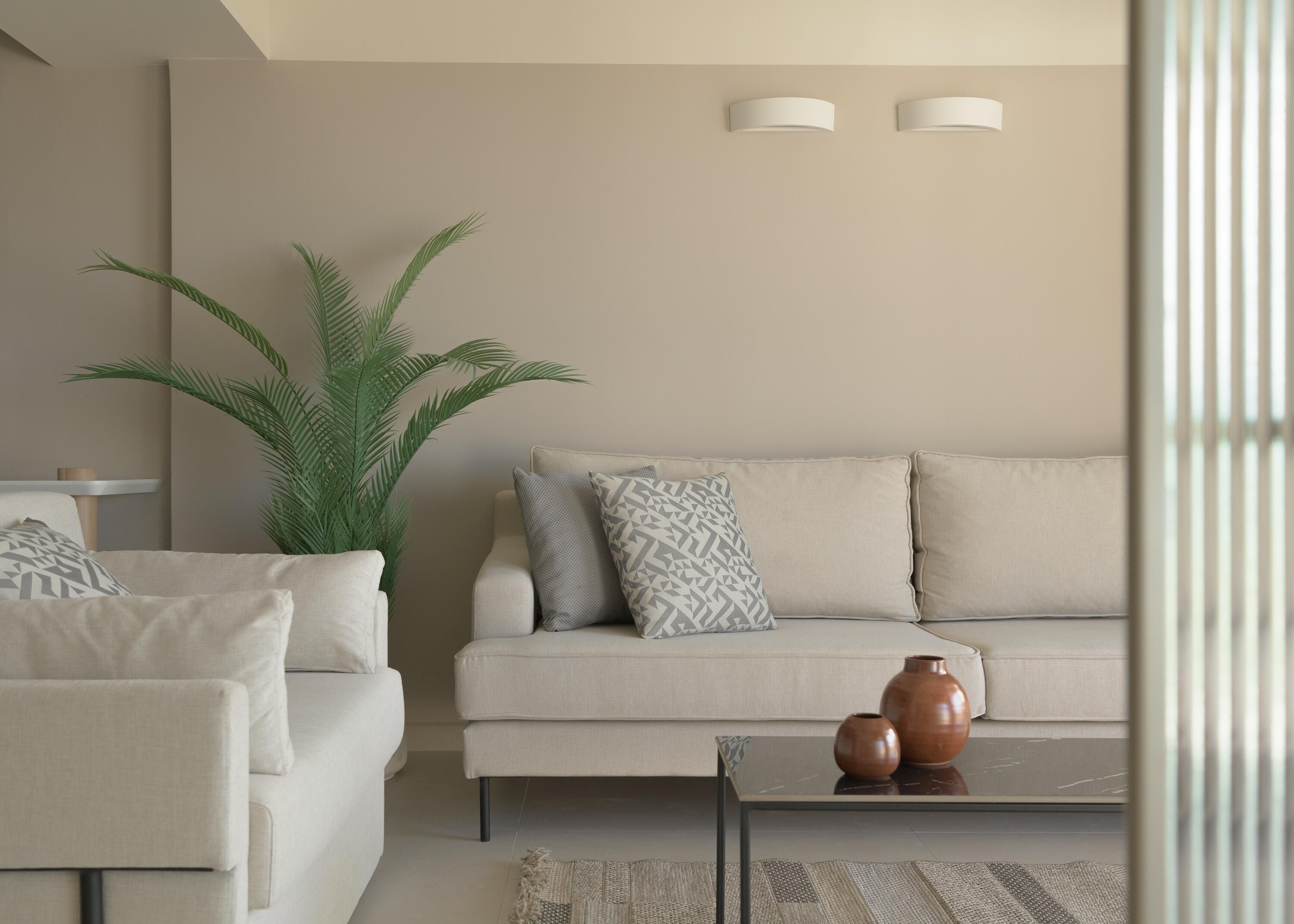 Una sala moderna con un sofá, un sillón y una mesa de centro con jarrones decorativos.
