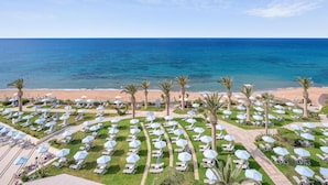 A resort with a beach view, rows of sun loungers, and palm trees. - Creta Star Hotel (Rethymno)