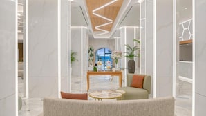 A modern lobby with marble walls, a wooden ceiling, and a central seating area with a coffee table and chairs. - Creta Star Hotel (Rethymno)