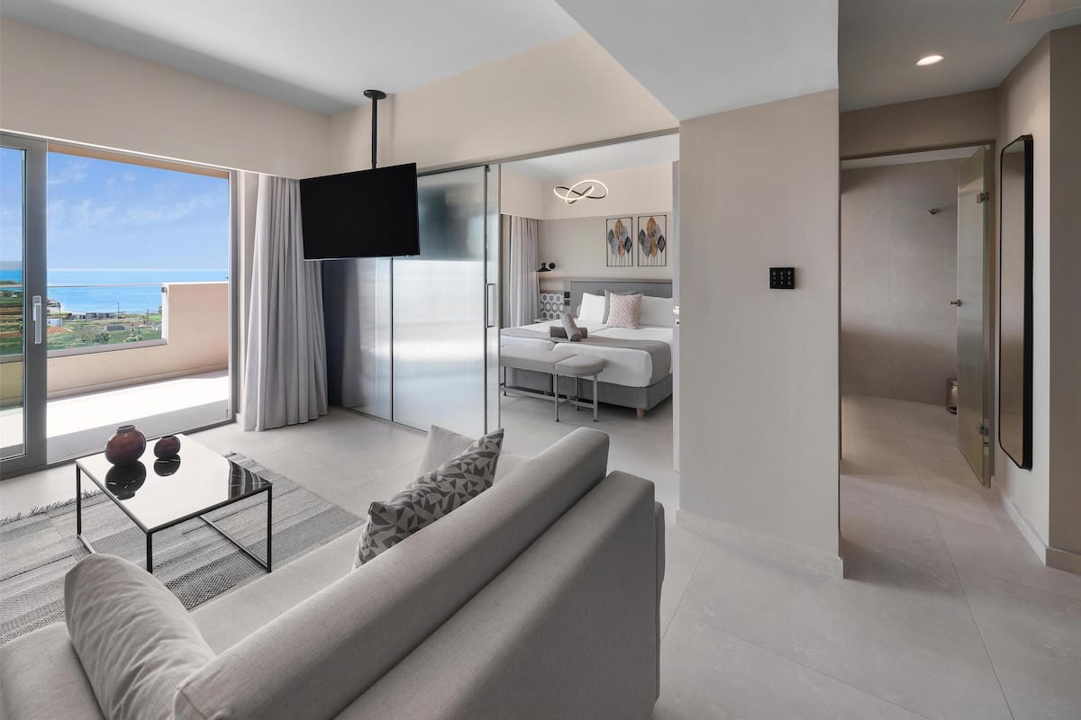 A modern hotel room with a balcony, a large bed, a TV, and a minimalist design.