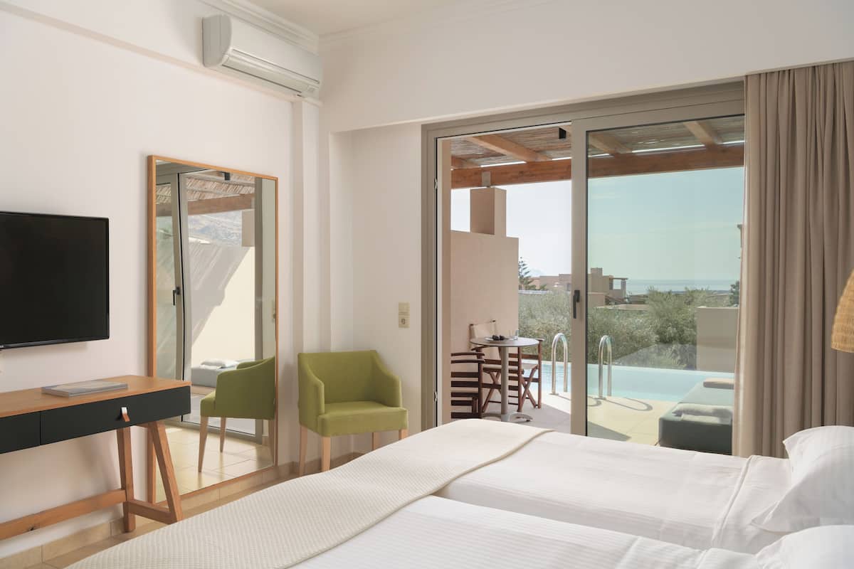 A hotel room with a bed, a desk, a chair, a TV, and a balcony with a pool.