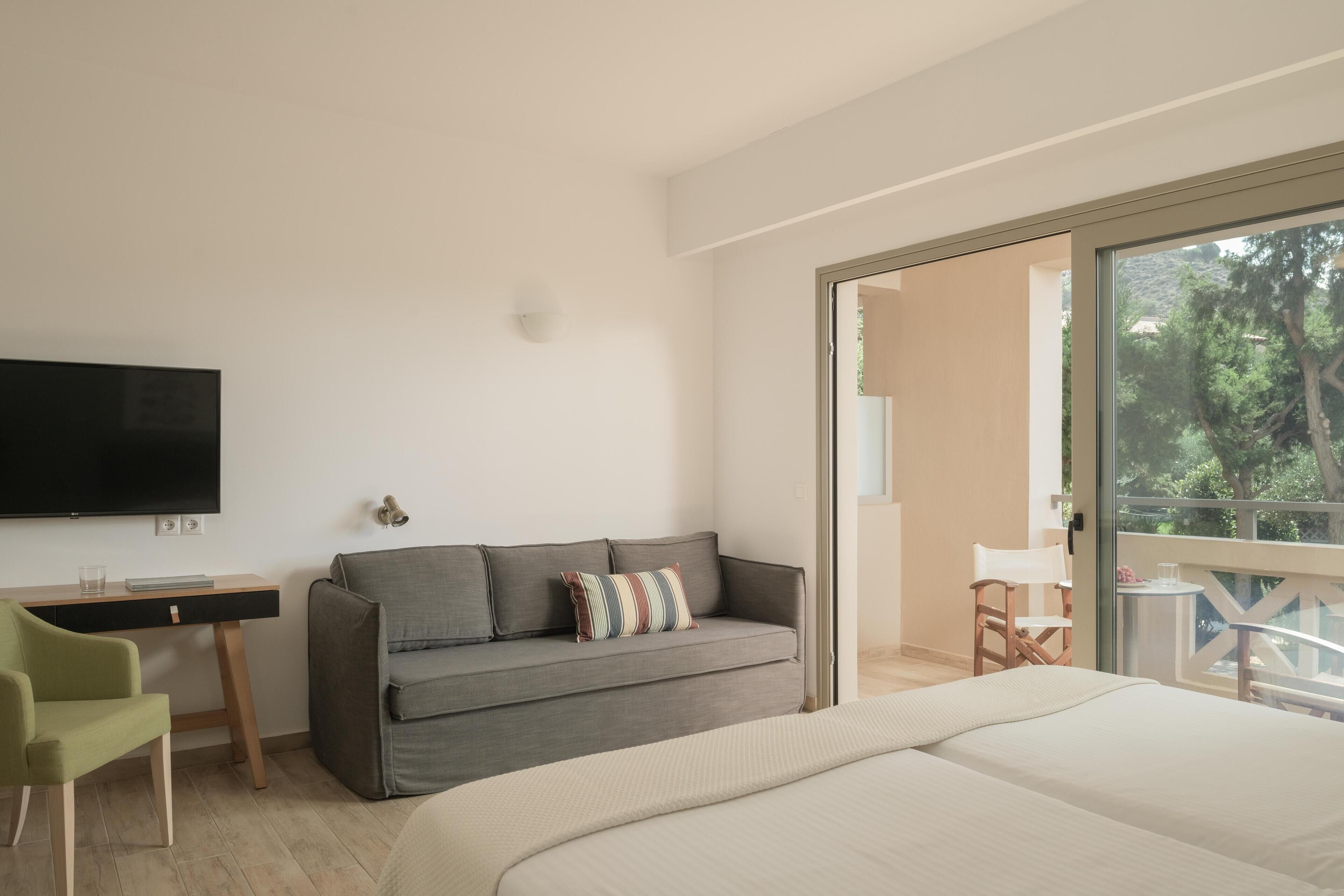 A bedroom with a bed, a sofa, a desk, and a TV.