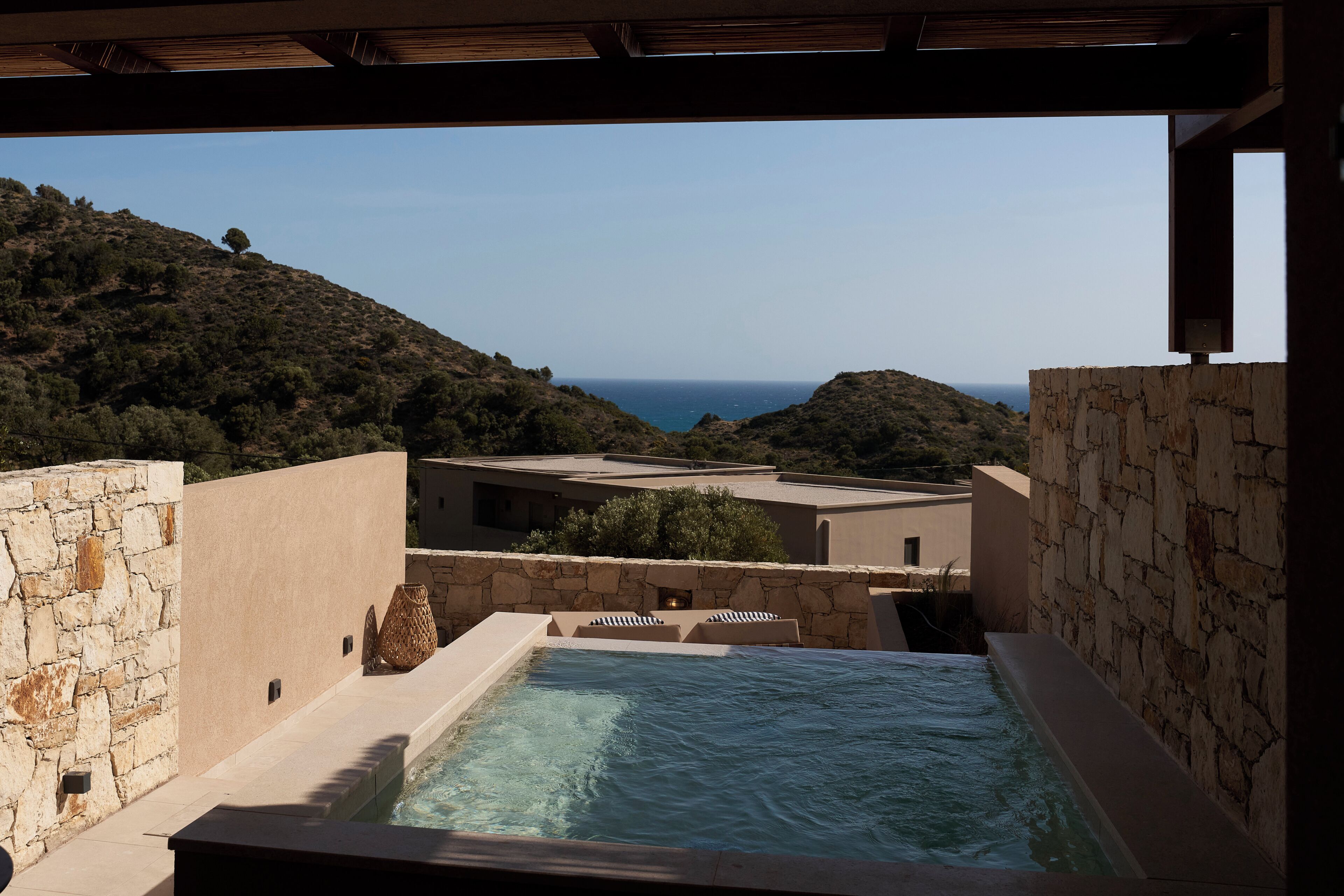 A hot tub with a view of the sea, stone walls, and a wooden ceiling.