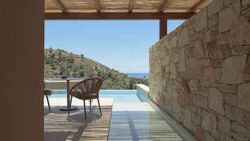 A stone wall, a wooden ceiling, and a view of a hill and sea.