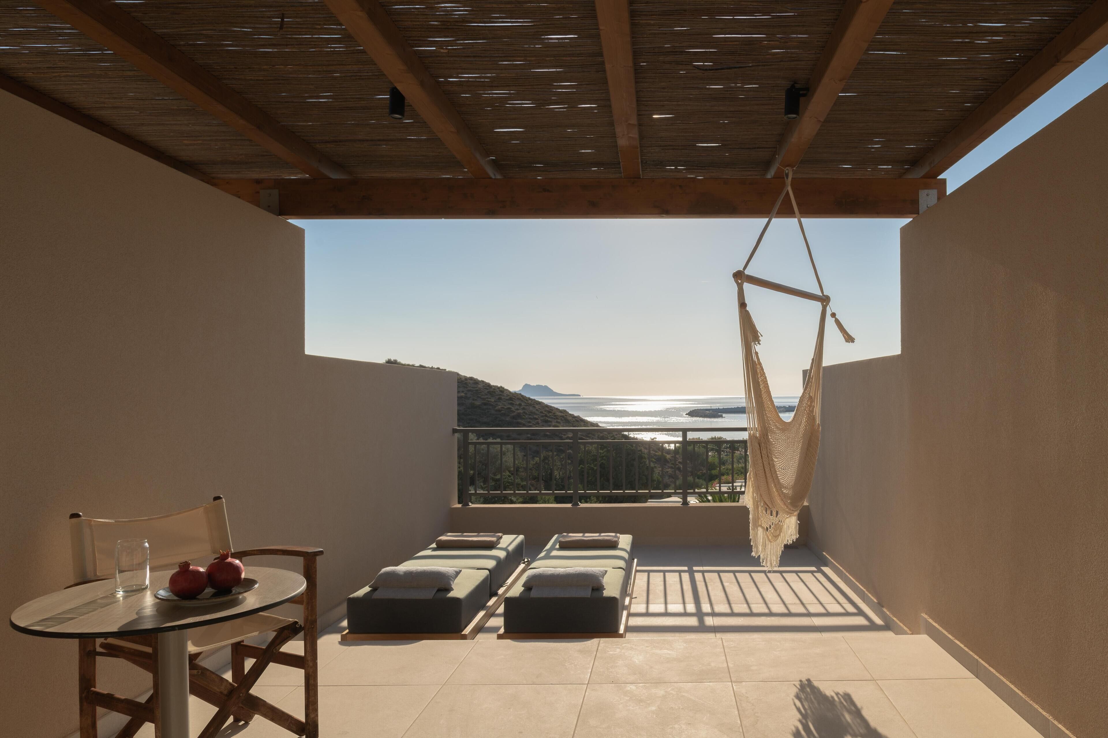 A balcony with a view of the sea, a hammock, and sun loungers.