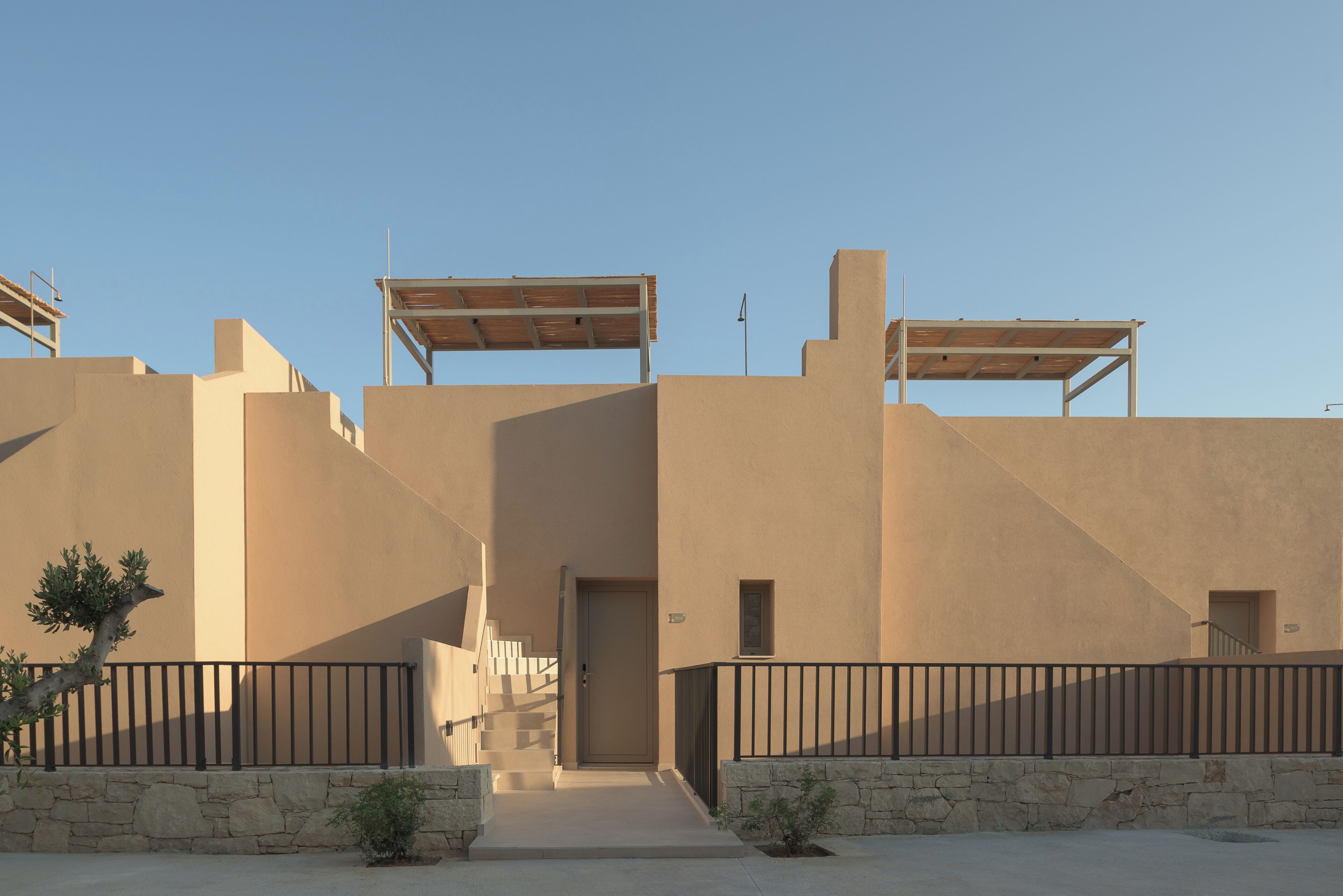 Un bâtiment à la façade beige, doté d’une porte centrale et d’un escalier menant à un étage supérieur.