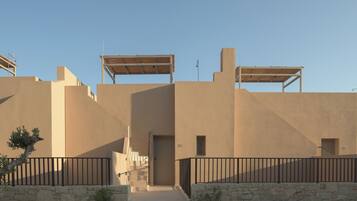Un bâtiment à la façade beige, doté d’une porte centrale et d’un escalier menant à un étage supérieur.