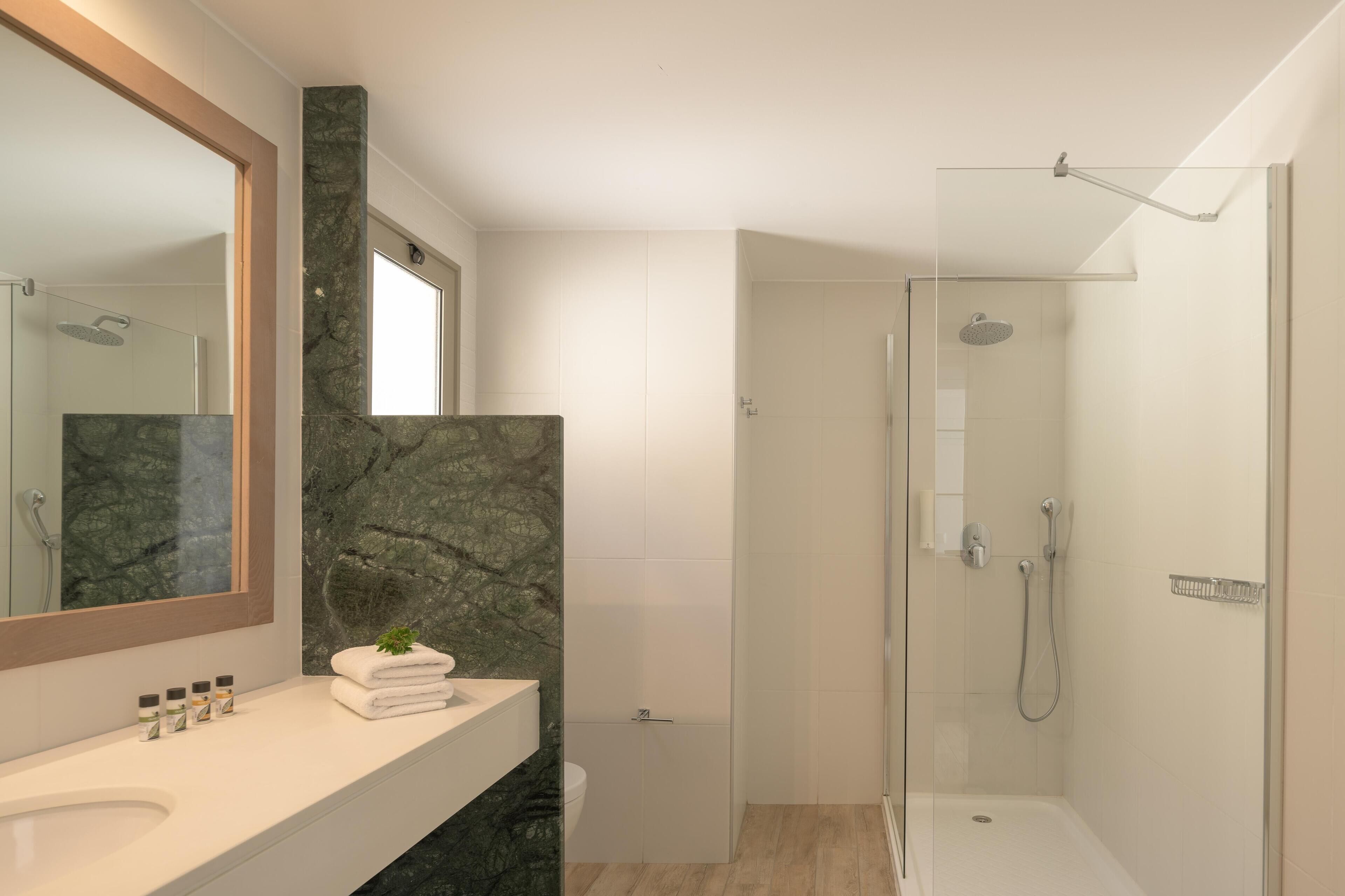 A modern bathroom with a marble sink, a large mirror, and a walk-in shower.