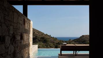 Un muro de piedra, una piscina y vistas al mar.