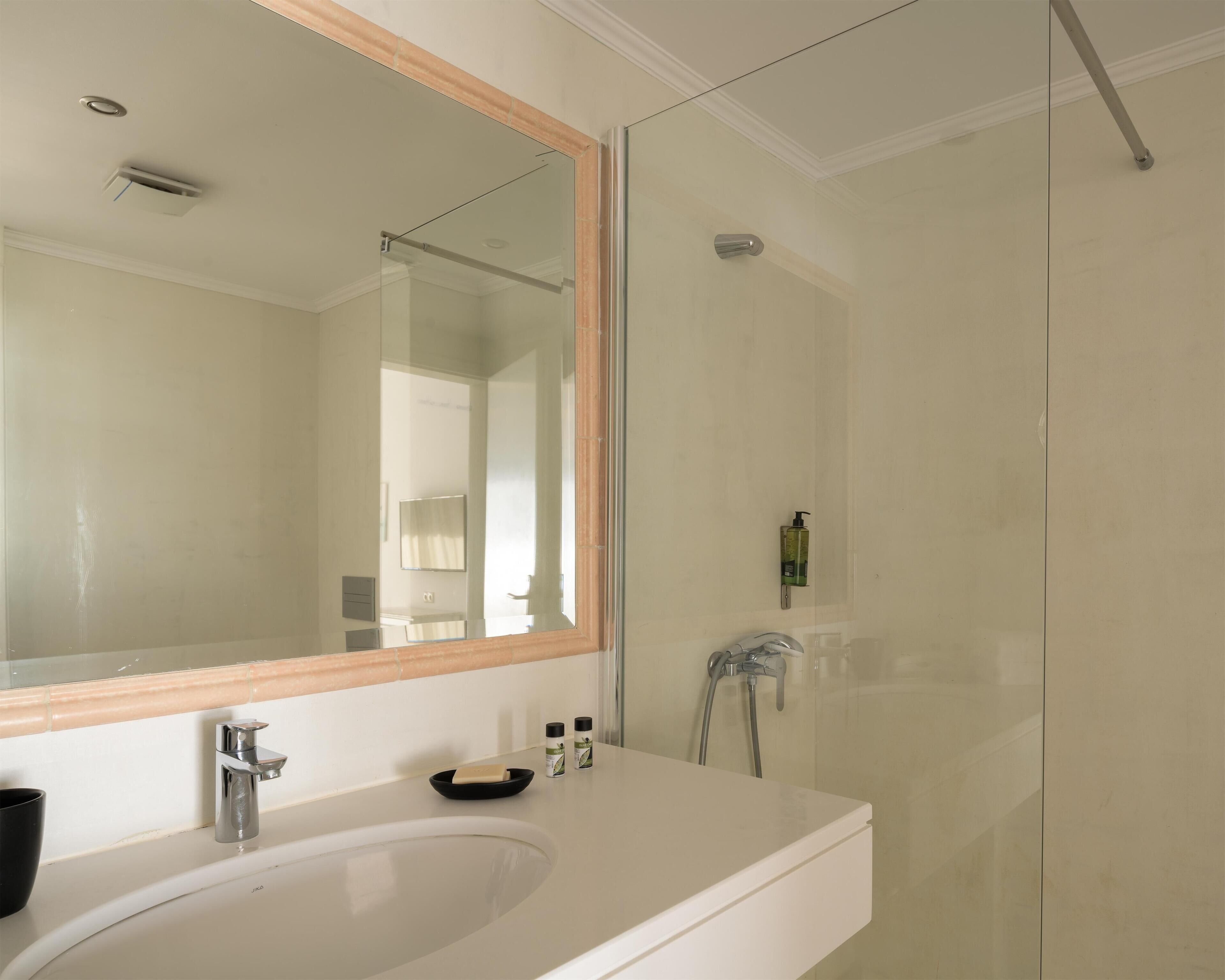 A modern bathroom with a large mirror, a sink, and a shower.