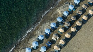 An aerial view of a beach with rows of umbrellas and sun loungers. - Paralos Irini Mare (Agios Vasileios)