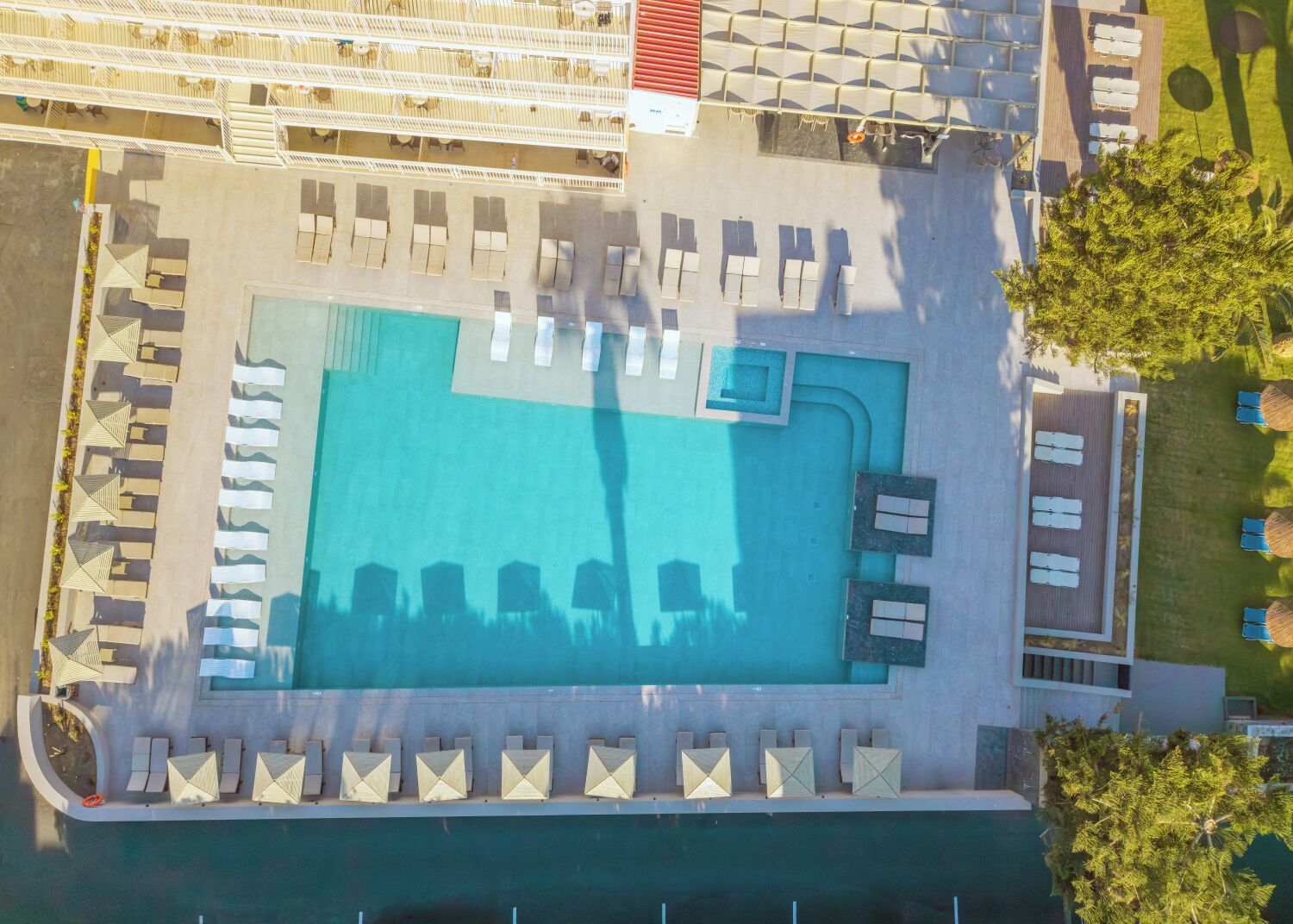 An aerial view of a swimming pool with sun loungers and a separate lounge area.