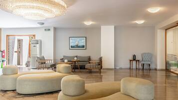 A spacious lobby with a modern chandelier, comfortable seating, and a framed picture on the wall.