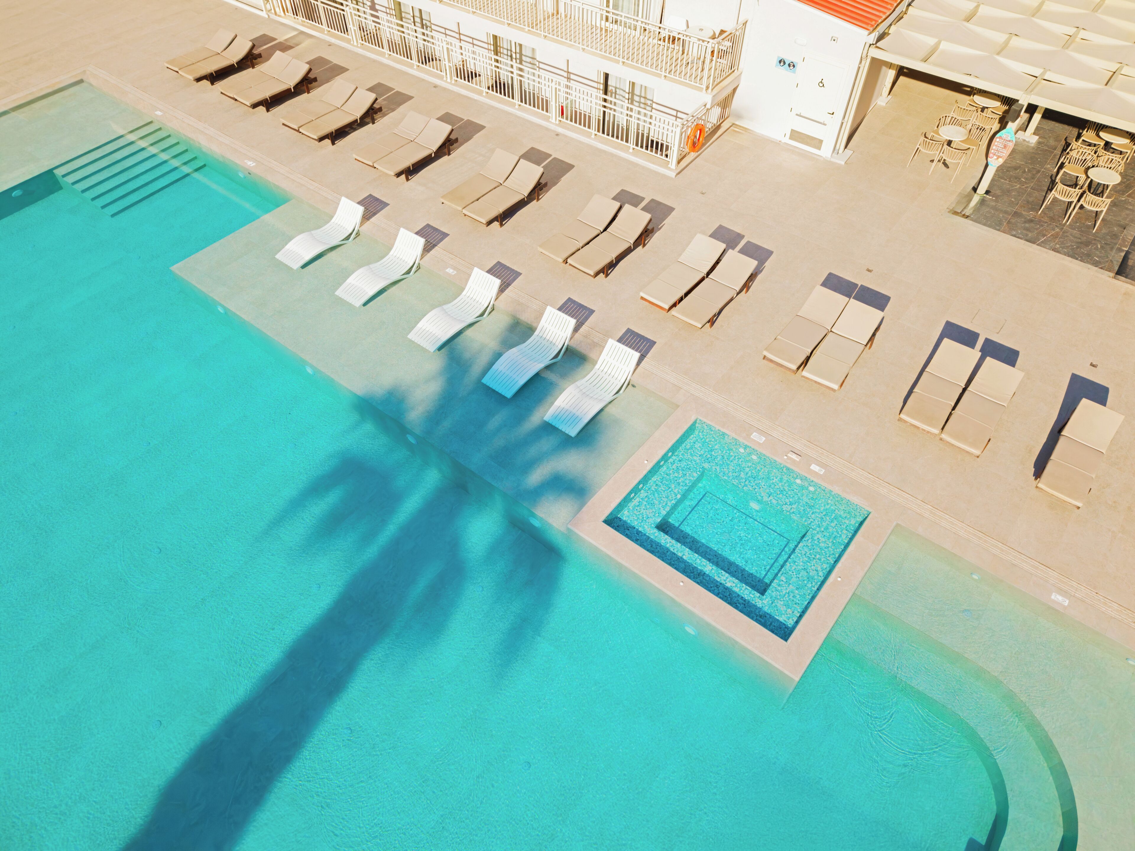 An aerial view of a swimming pool with sun loungers and a separate section for diving.