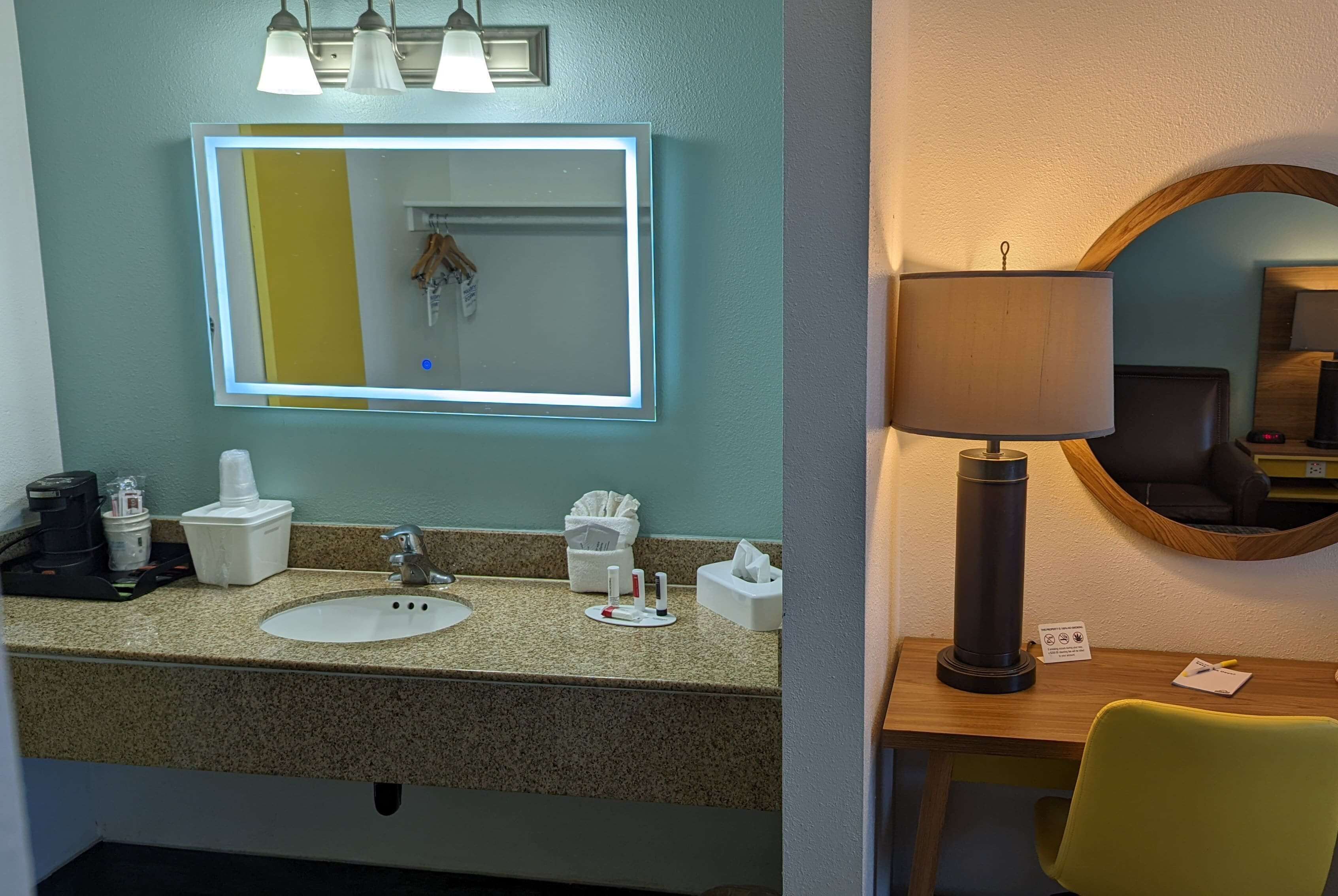 Een hotelbadkamer met een wastafel, spiegel en toiletartikelen.