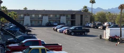 A parking lot with various vehicles, including cars and trucks, in front of a building with multiple windows and balconies.