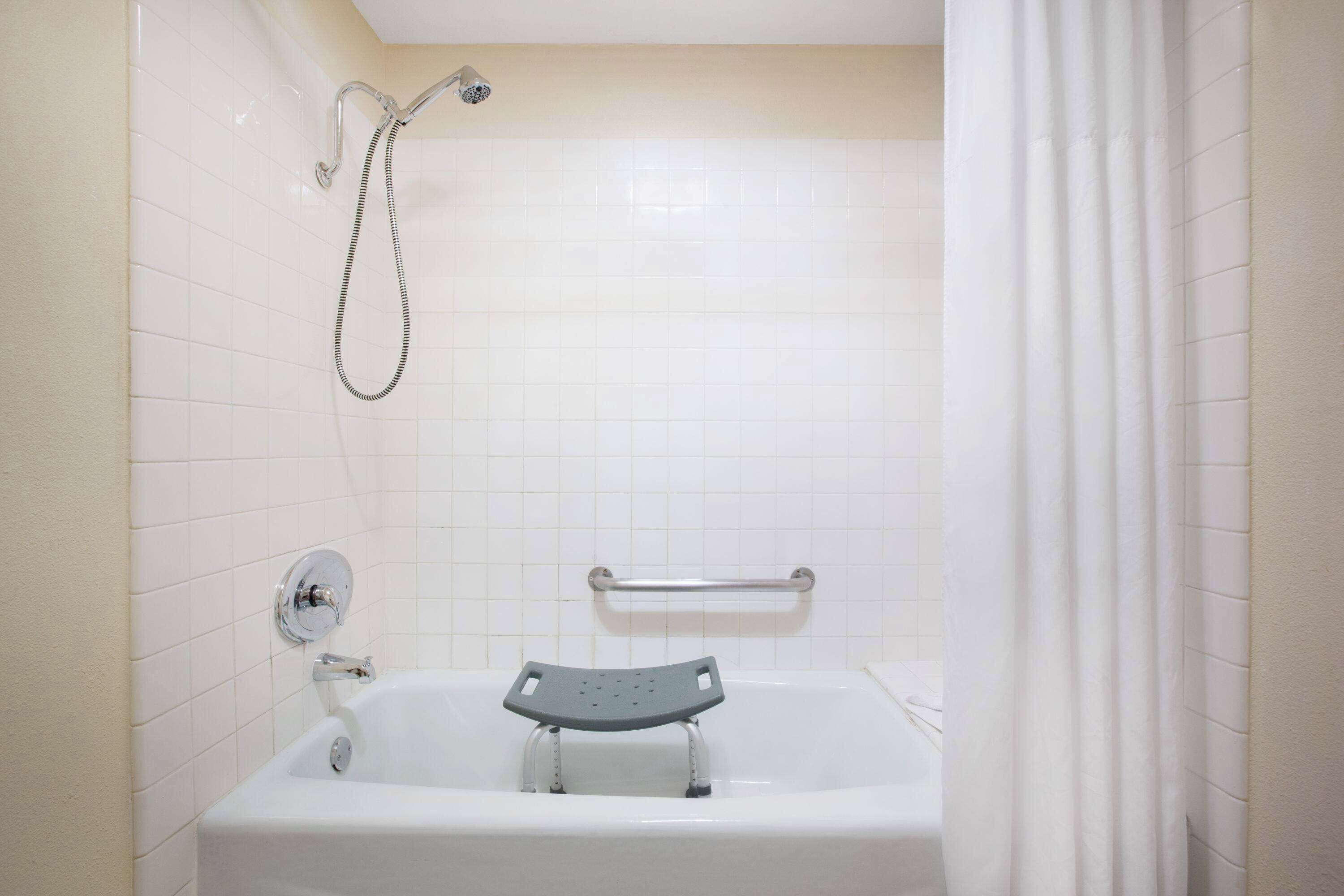 Een badkamer met een bad, een douchekop en een handgreep.
