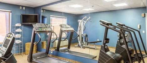Un gimnasio con cintas de correr, elípticas y una bicicleta estática.