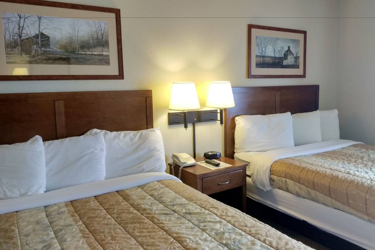 Ett hotellrum med två sängar, ett nattduksbord med en lampa, en telefon och en fjärrkontroll.