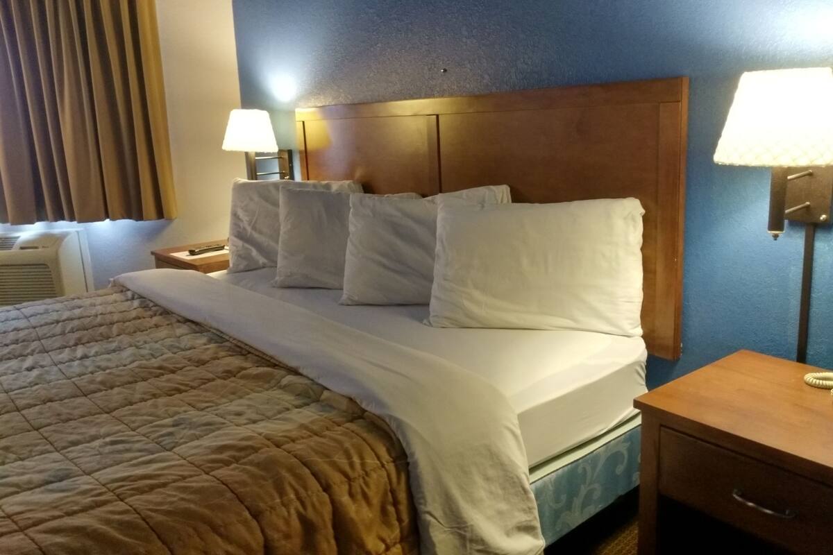 Ett hotellrum med en säng, ett nattduksbord, en bordslampa och en vägglampa.