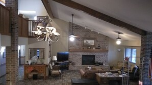 A spacious living room with a fireplace, a television, and a chandelier.