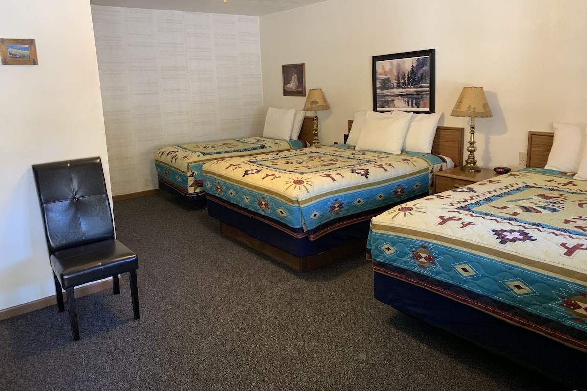 A hotel room with two beds, a chair, and a ceiling fan.