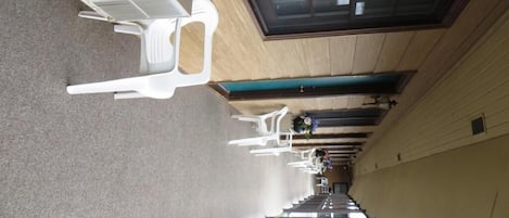 A corridor with white chairs and a potted plant.