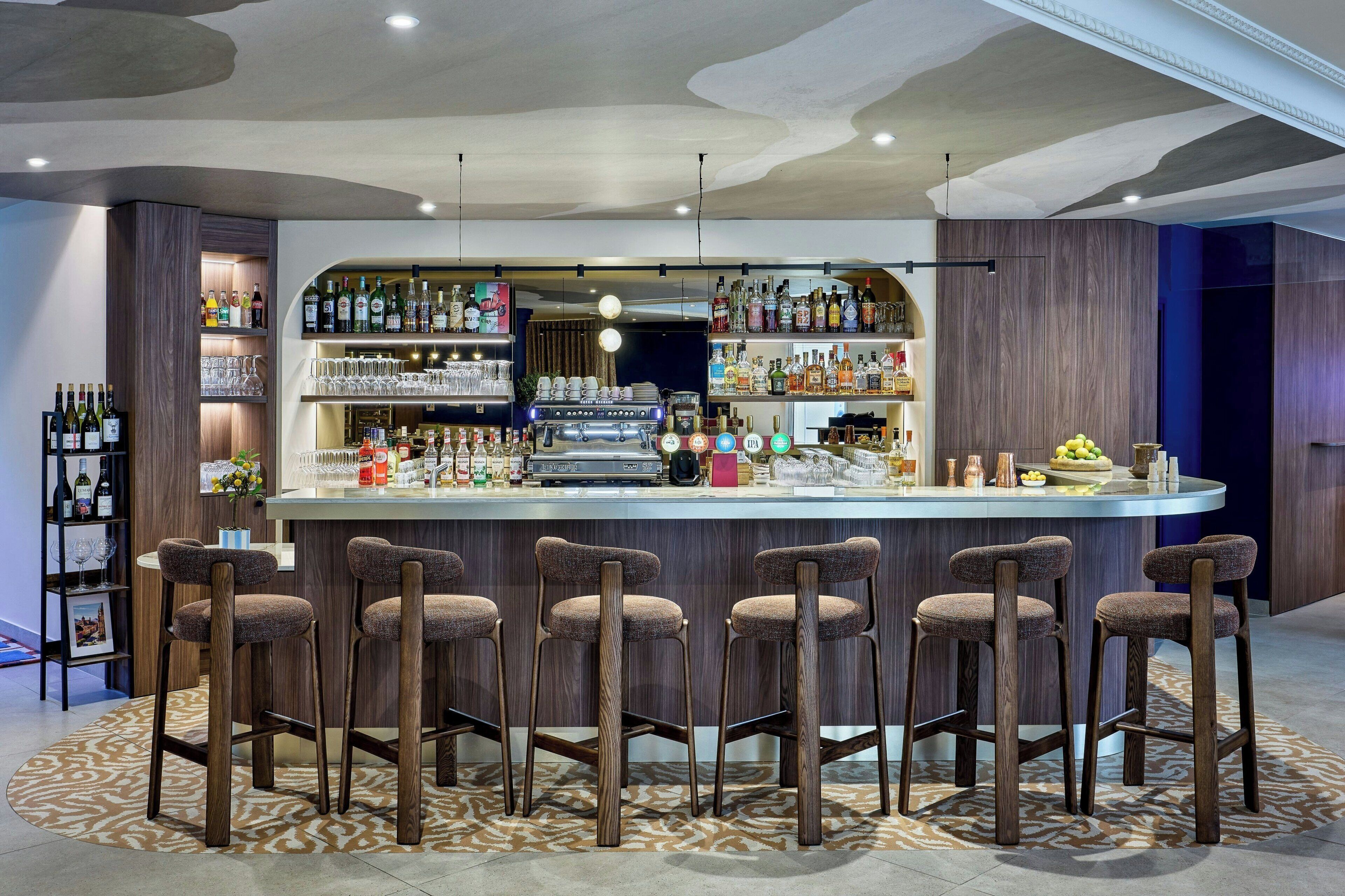 Un espace bar doté d’un bar central, de nombreuses étagères à bouteilles et de tabourets de bar.