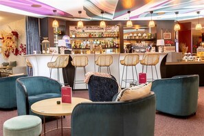 Eine Bar mit Theke, Barhocker und einer Sitzecke mit Sofas und einem runden Tisch.