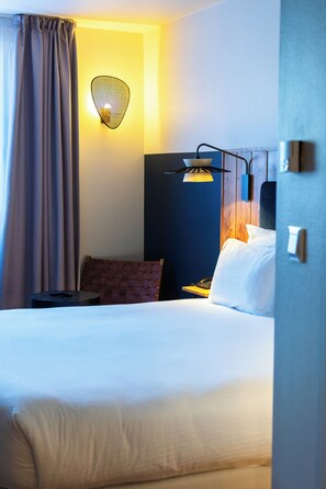 A hotel room with a bed, a desk, a lamp, and a wall-mounted light fixture. - Four Points by Sheraton Paris Charles de Gaulle Airport (Roissy-en-France)