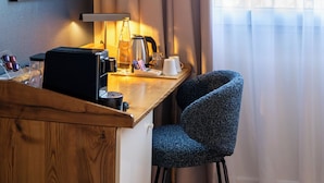 A hotel room with a wooden desk, a chair, a bed, a window with curtains, and a framed picture on the wall. - Four Points by Sheraton Paris Charles de Gaulle Airport (Roissy-en-France)