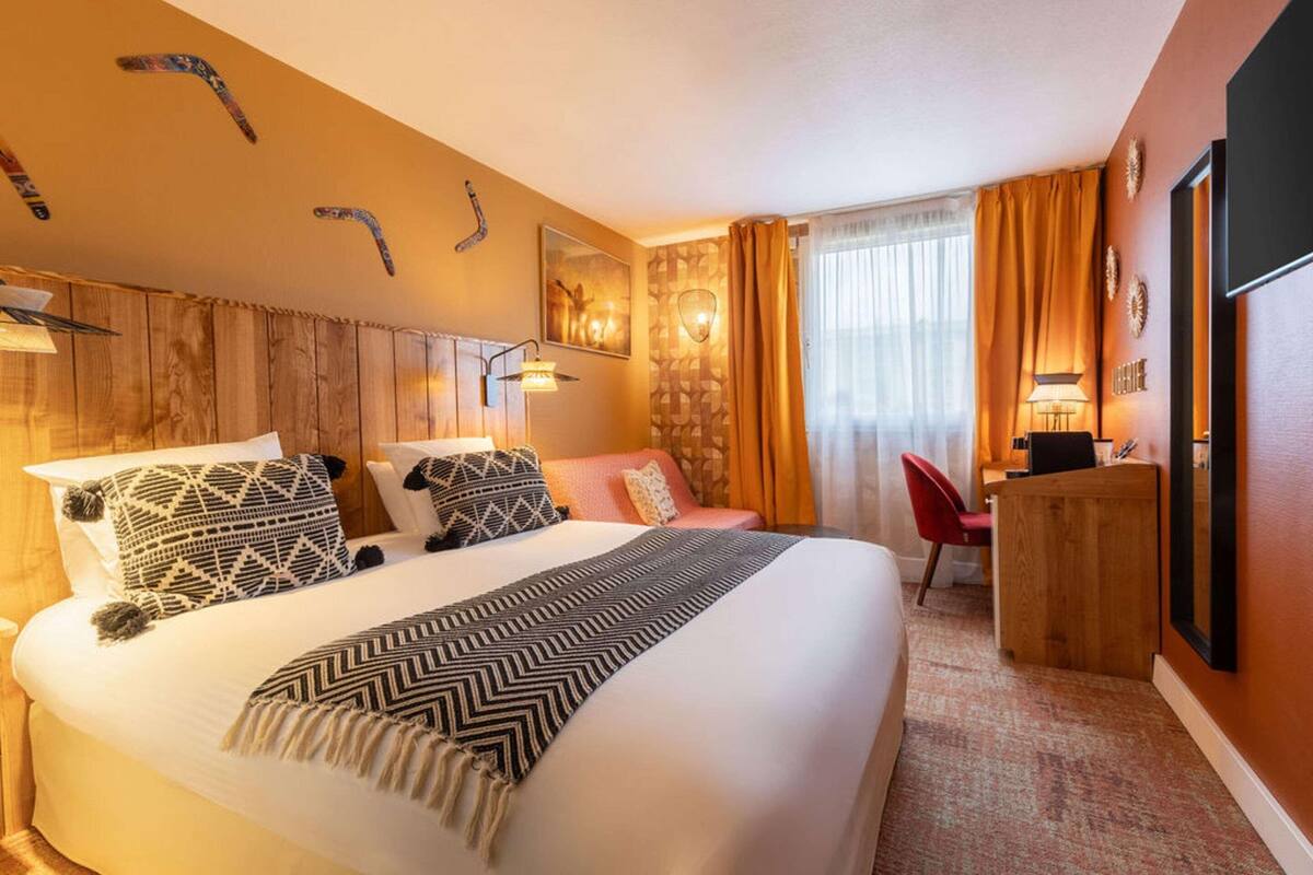 Ein Hotelzimmer mit einem großen Bett, einem Schreibtisch, einem Sessel und einem Fernseher.