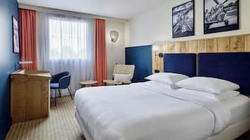Een hotelkamer met een bed, een bureau, een stoel, een kleine tafel en een wandlamp.