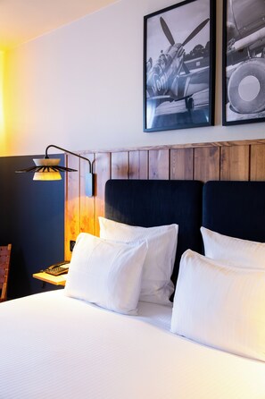 A hotel room with a bed, a nightstand, a lamp, and two framed pictures on the wall.