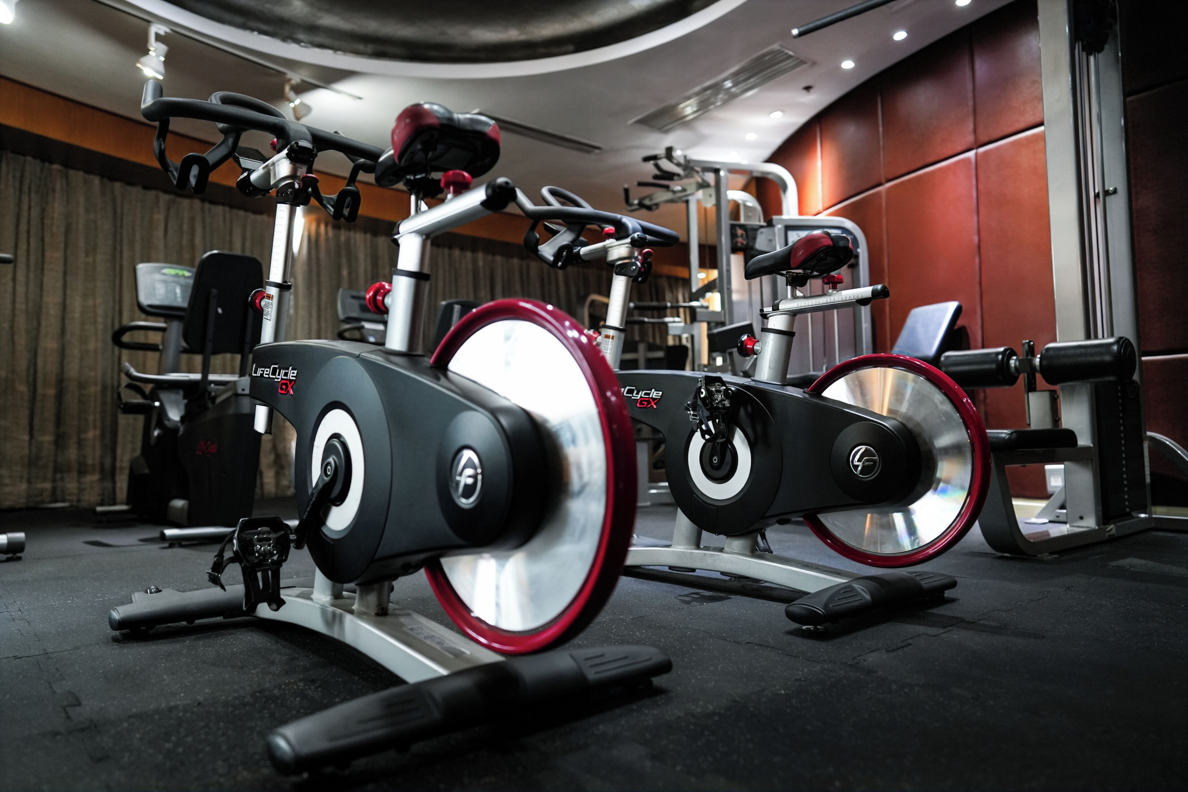 A stationary bike with a digital display, a weight stack, and a red seat.