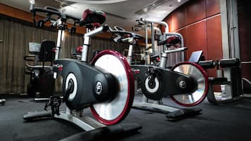 A stationary bike with a digital display, a weight stack, and a red seat.