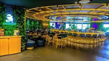 A bar area with a curved counter, seating, and a neon sign.