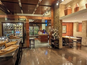 Un ristorante con zona bar, tavoli in legno e una parete in pietra.