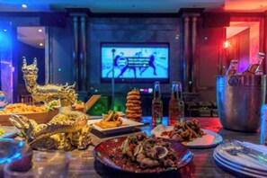 A dining area with a variety of dishes, a television screen, and a bar area with bottles. - New Coast Hotel Manila (Manila)