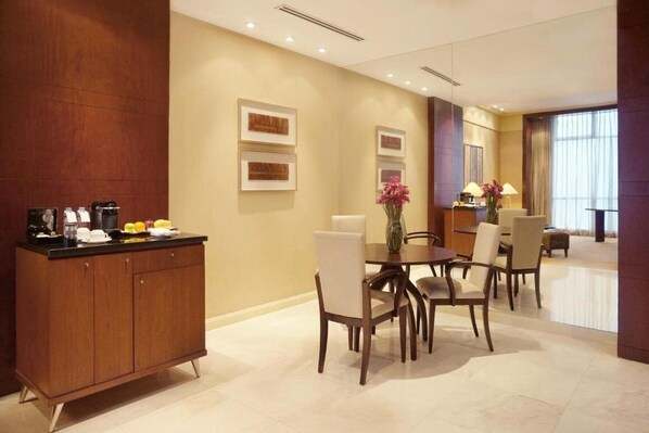 A modern dining area with a wooden cabinet, a round table, and several chairs. - New Coast Hotel Manila (Manila)