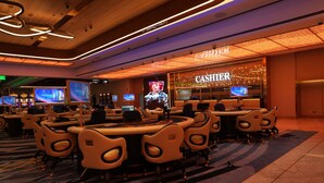 A casino floor with multiple gaming tables and chairs, a cashier area, and digital screens displaying various content. - New Coast Hotel Manila (Manila)