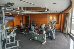 Een sportschool met diverse fitnessapparaten, een klok en een waterdispenser.